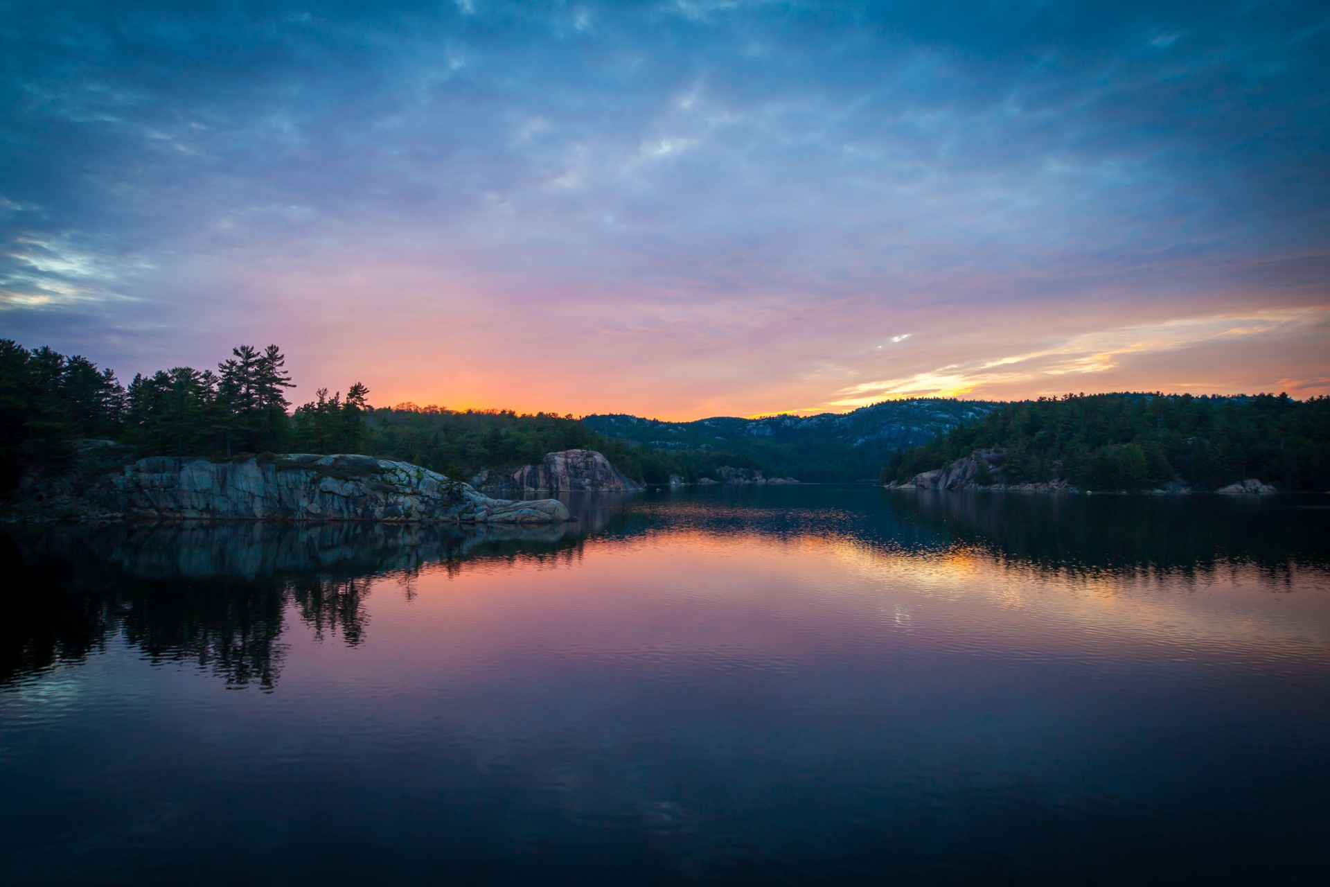 Dramatic Sunset over the granite rock shoreline of the clear water lake, Killarney Provincial Park, Ontario, Canada